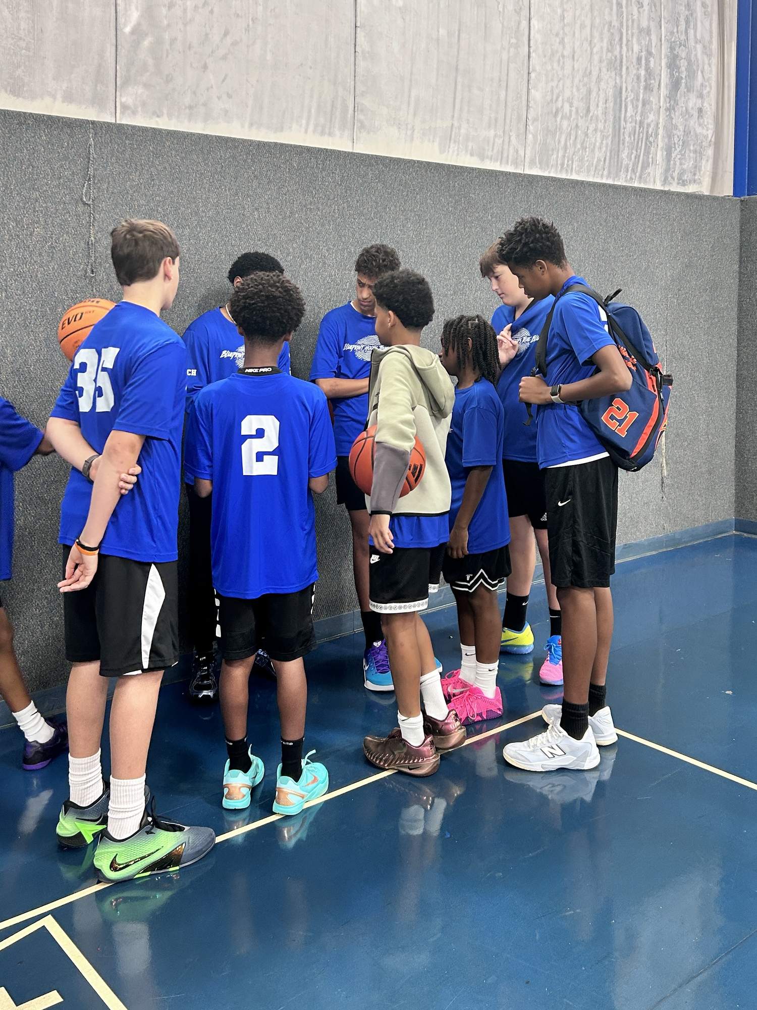 BLUEprint Hoops TRUE BLUE Winter Ball players in blue shirts huddled around their coach