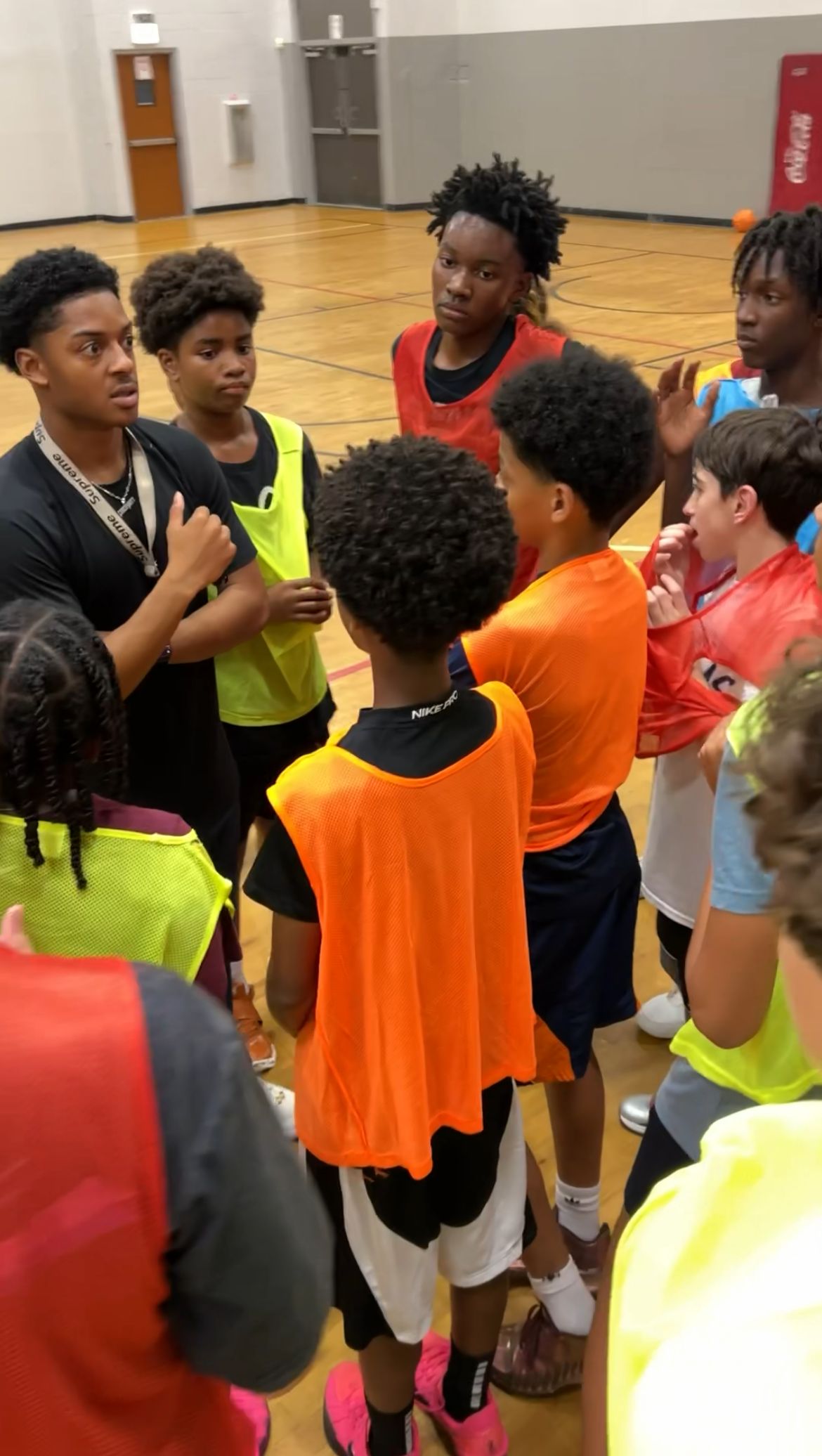 Players in tryout pinnies huddled around a coach at a BLUEprint Hoops TRUE BLUE tryout in Chicago